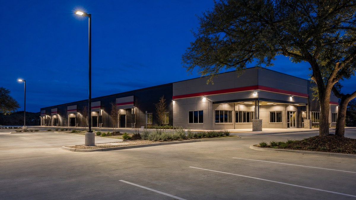 Texas industrial office building at dusk with full-cutoff LED wall packs and LED area lights on poles in the parking lot